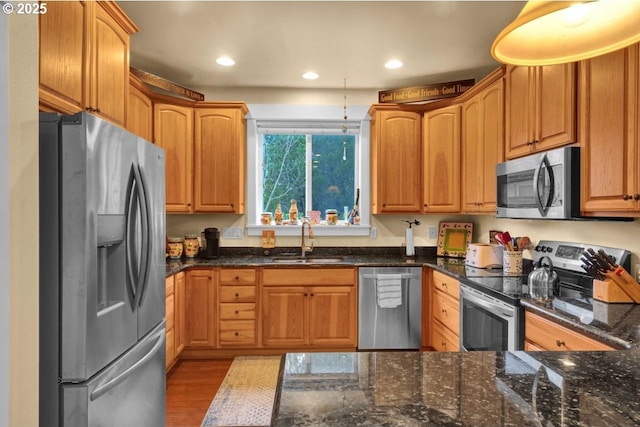 kitchen featuring a sink, dark stone countertops, recessed lighting, and stainless steel appliances