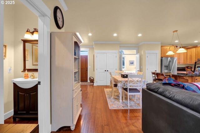 living area featuring recessed lighting, wood finished floors, baseboards, and ornamental molding