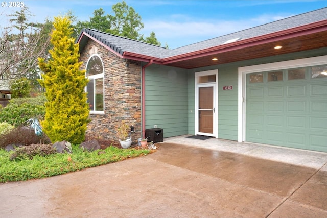 exterior space with stone siding, an attached garage, and concrete driveway