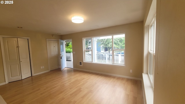 interior space with baseboards, multiple closets, visible vents, and light wood-style floors