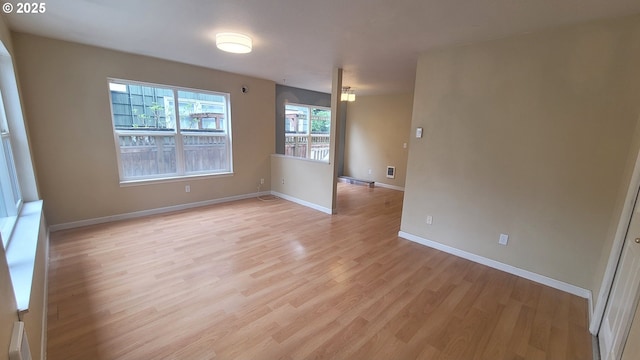 unfurnished room with light wood-type flooring, baseboards, and visible vents