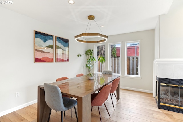 dining room with recessed lighting, a fireplace, light wood-style flooring, and baseboards