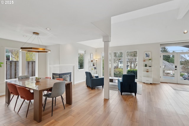 dining space with a glass covered fireplace, plenty of natural light, and light wood-style floors