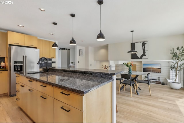kitchen with high end fridge, a center island, light wood-style floors, a sink, and light brown cabinetry