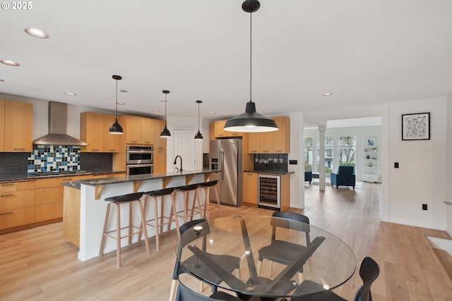 dining area featuring light wood-type flooring, decorative columns, beverage cooler, and recessed lighting