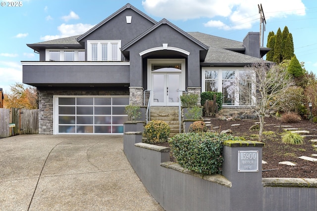 view of front of property featuring concrete driveway, fence, stone siding, and stucco siding