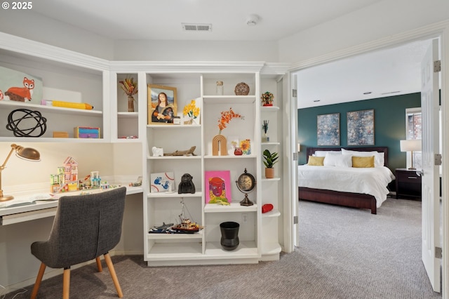 carpeted bedroom with built in desk and visible vents