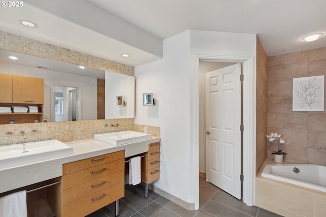 bathroom with tasteful backsplash, double vanity, tile patterned floors, tiled bath, and a sink
