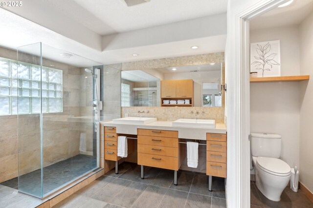 bathroom featuring a shower with door, vanity, and backsplash