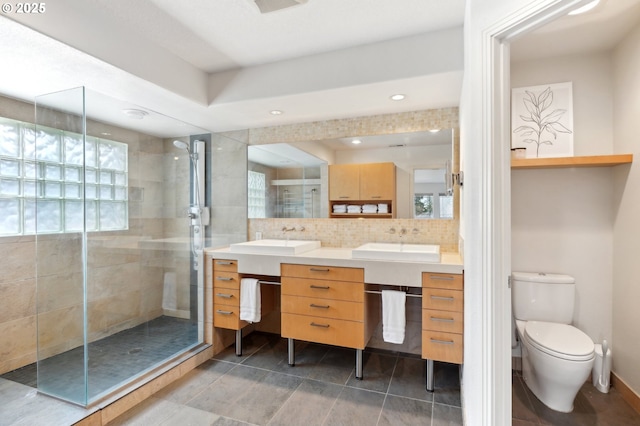 bathroom with toilet, a stall shower, vanity, and decorative backsplash