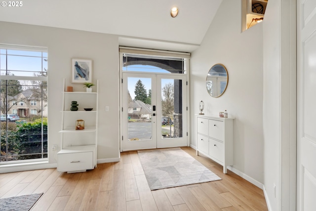 entryway with french doors, light wood finished floors, baseboards, and a healthy amount of sunlight