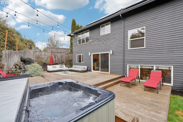 wooden terrace with outdoor lounge area, fence, and a hot tub