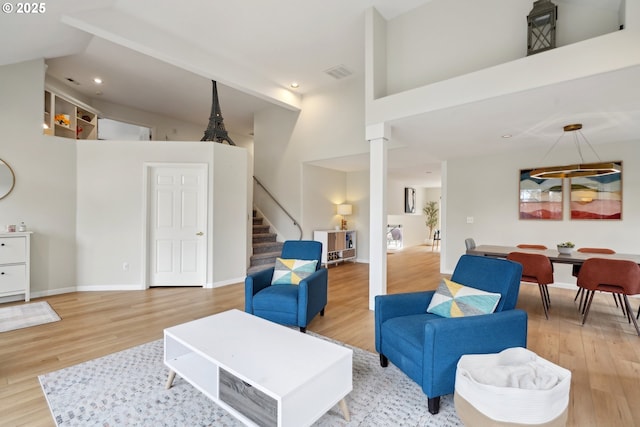 living room with a towering ceiling and light wood-type flooring