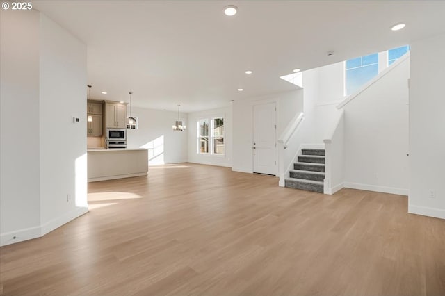 unfurnished living room with light hardwood / wood-style flooring and a chandelier