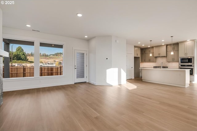 unfurnished living room featuring light hardwood / wood-style flooring and sink