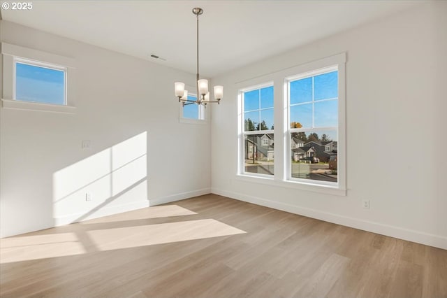 unfurnished dining area featuring light hardwood / wood-style flooring and an inviting chandelier