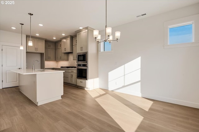 kitchen with gray cabinets, sink, hanging light fixtures, and appliances with stainless steel finishes