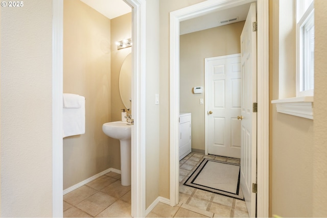 bathroom with washer / dryer, baseboards, visible vents, and a sink