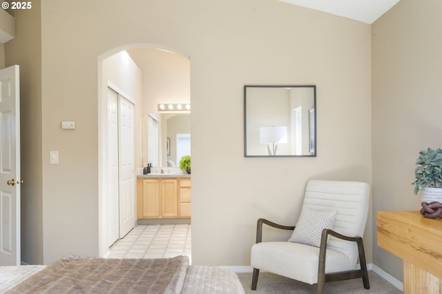 interior space with arched walkways, a closet, connected bathroom, and baseboards