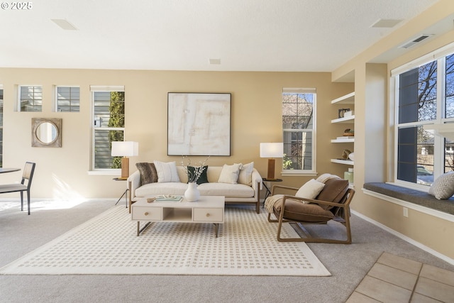 living room featuring carpet, tile patterned flooring, visible vents, and baseboards