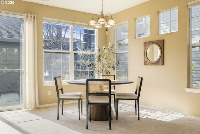 carpeted dining space with a healthy amount of sunlight, baseboards, and an inviting chandelier