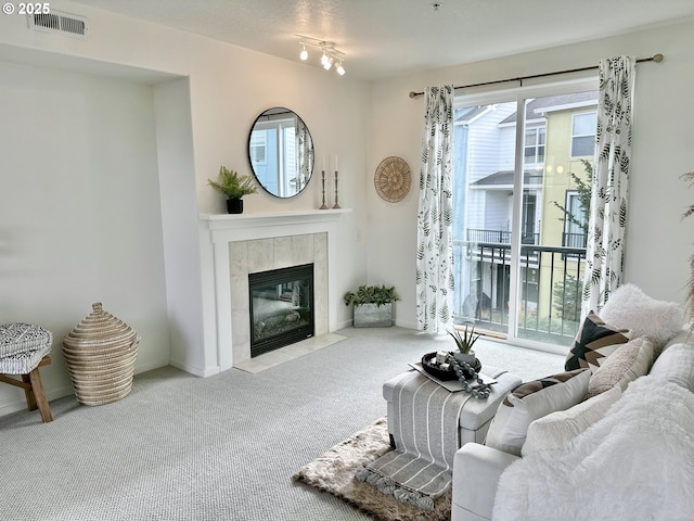 living area featuring carpet floors, baseboards, a fireplace, and visible vents