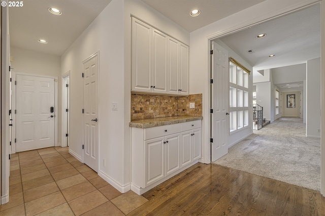 corridor featuring recessed lighting, light colored carpet, stairway, and baseboards