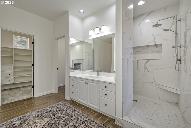 bathroom with a marble finish shower, baseboards, wood tiled floor, vanity, and recessed lighting