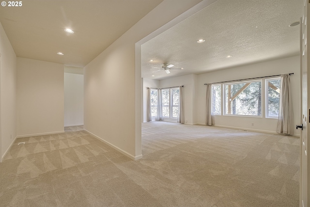 spare room with recessed lighting, light colored carpet, a textured ceiling, and baseboards