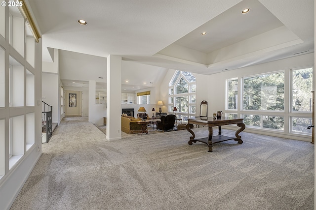 office area featuring a tray ceiling, a fireplace, recessed lighting, and light colored carpet