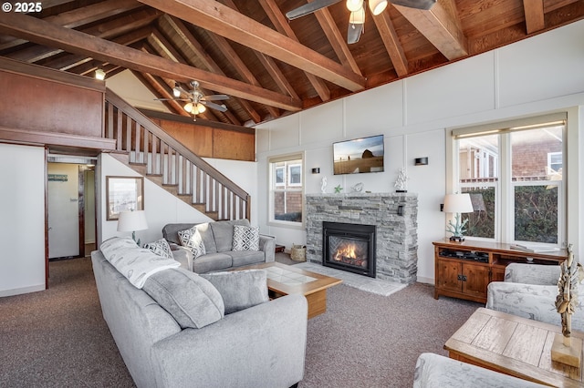 living room with a stone fireplace, beamed ceiling, high vaulted ceiling, and ceiling fan