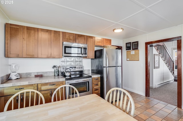 kitchen featuring a baseboard heating unit, light colored carpet, and appliances with stainless steel finishes