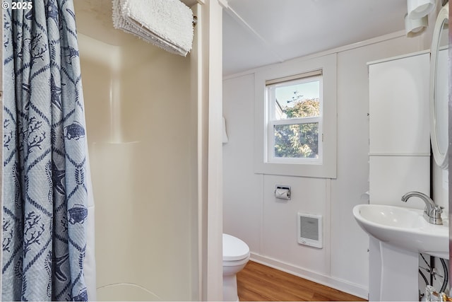 bathroom featuring toilet, sink, heating unit, a shower with shower curtain, and hardwood / wood-style flooring