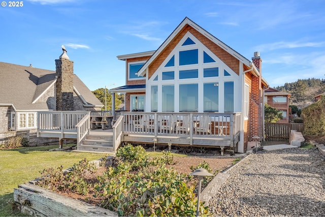 rear view of property featuring a deck and a lawn