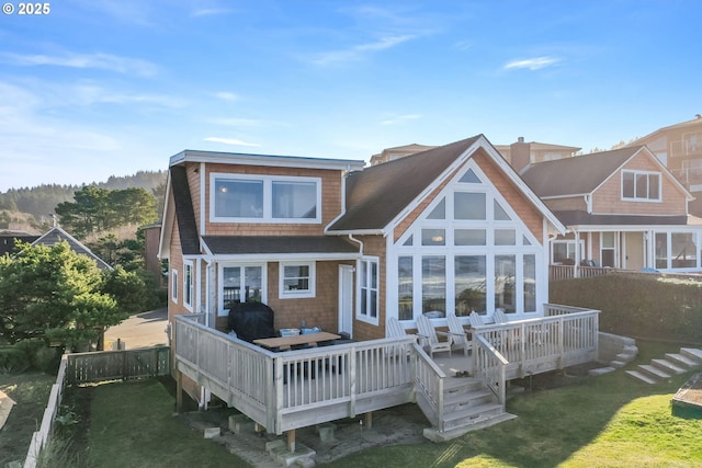 rear view of property featuring a wooden deck and a lawn