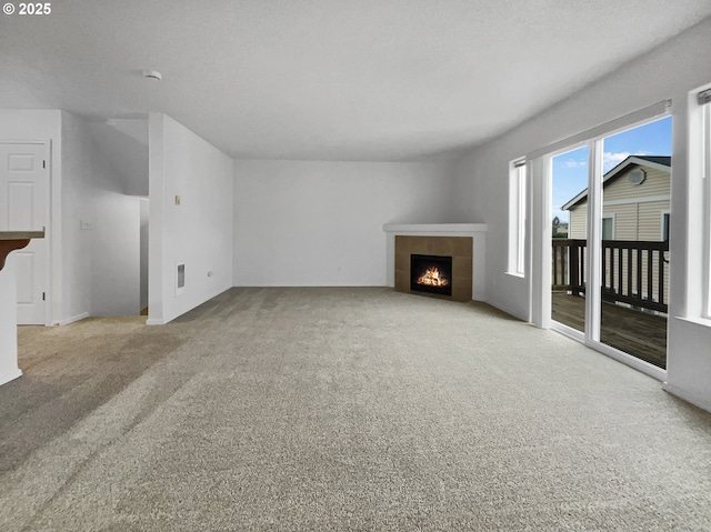 unfurnished living room with a tiled fireplace and carpet flooring