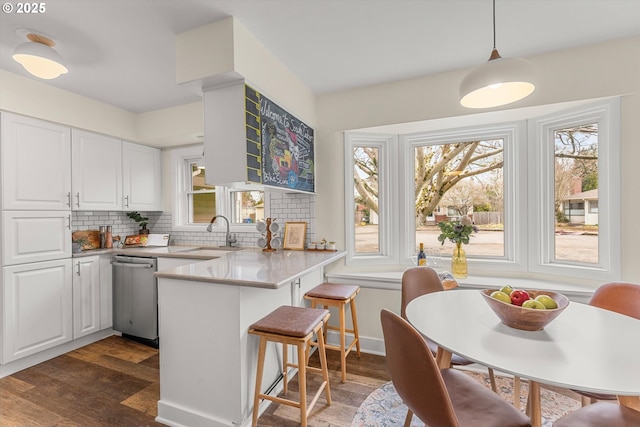 kitchen with decorative backsplash, dishwasher, a peninsula, white cabinetry, and a sink