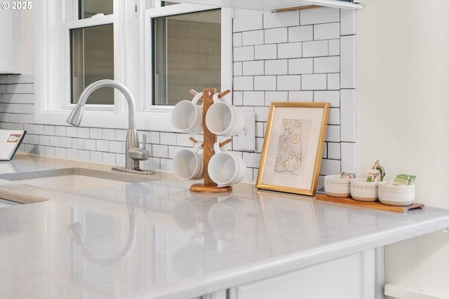 room details with white cabinets, stainless steel countertops, decorative backsplash, and a sink