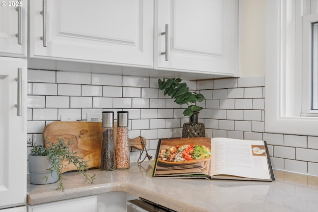 details with tasteful backsplash, white cabinetry, and light stone countertops