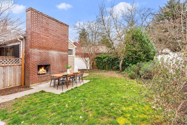 view of yard featuring a fireplace, fence, and a patio