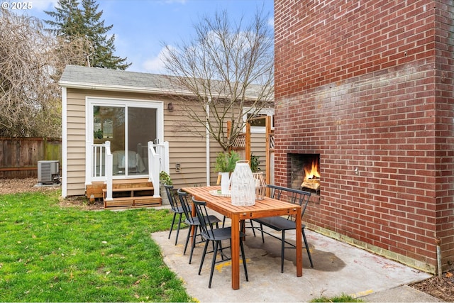 view of patio / terrace with entry steps, an outdoor brick fireplace, cooling unit, and fence