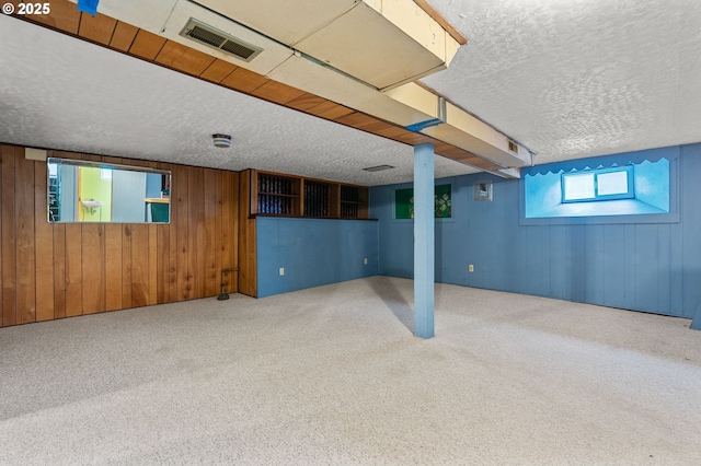 basement featuring carpet, visible vents, and a textured ceiling