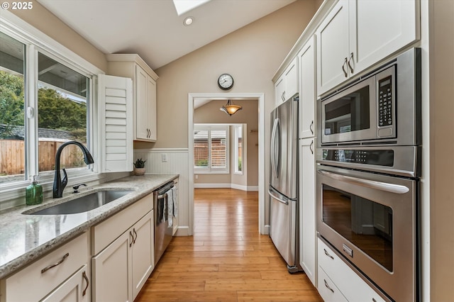 1722 Sequoia Ct, Forest Grove, OR 97116 - kitchen with appliances with stainless steel finishes, vaulted ceiling, light wood-style floors, wainscoting, and light stone counters