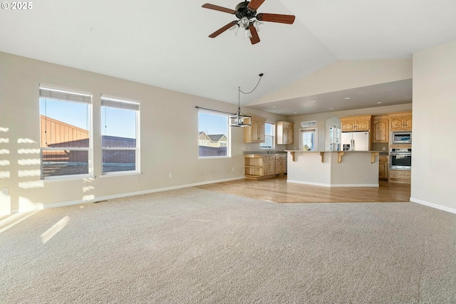 unfurnished living room with lofted ceiling, sink, light carpet, and ceiling fan