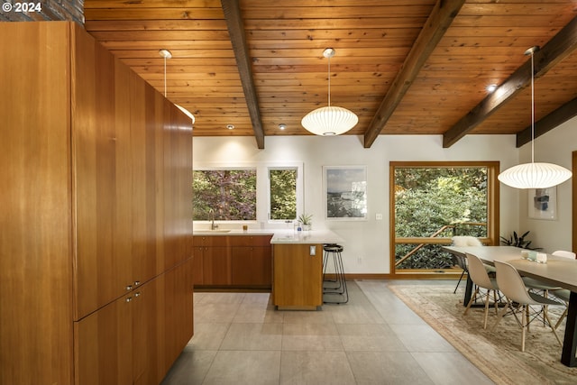 kitchen with brown cabinets, light countertops, a wealth of natural light, beamed ceiling, and wood ceiling