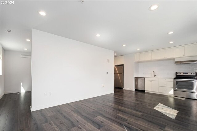 1480 N Jarrett St Unit 103, Portland, OR 97217 - kitchen with appliances with stainless steel finishes, a sink, white cabinetry, dark wood-type flooring, and under cabinet range hood