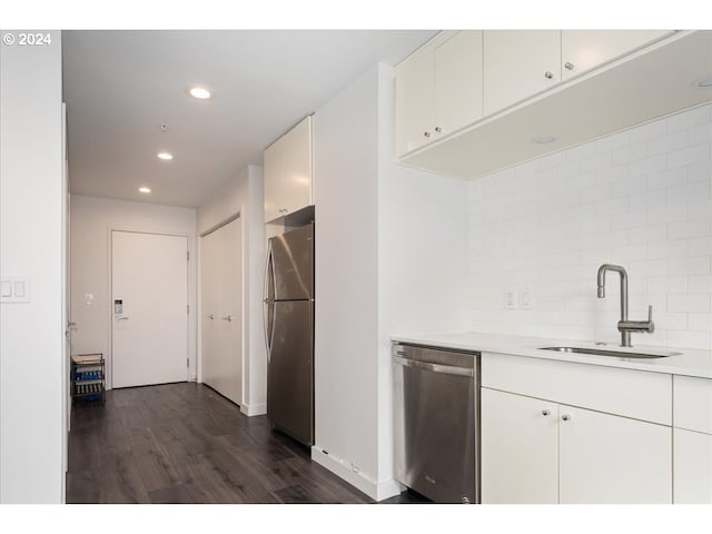 kitchen with appliances with stainless steel finishes, a sink, light countertops, recessed lighting, and dark wood-type flooring