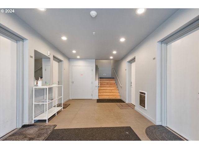 corridor featuring recessed lighting, heating unit, baseboards, and stairway