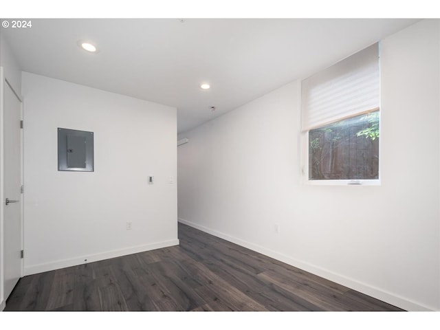 empty room featuring recessed lighting, dark wood-style flooring, baseboards, and electric panel