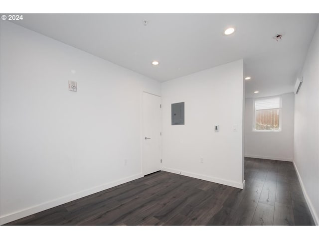 unfurnished room featuring dark wood-style flooring, recessed lighting, baseboards, and electric panel